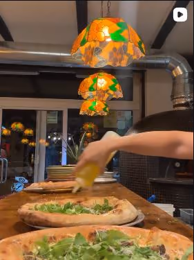 Un raig d'oli d'oliva sobre pizzes amb rúcula